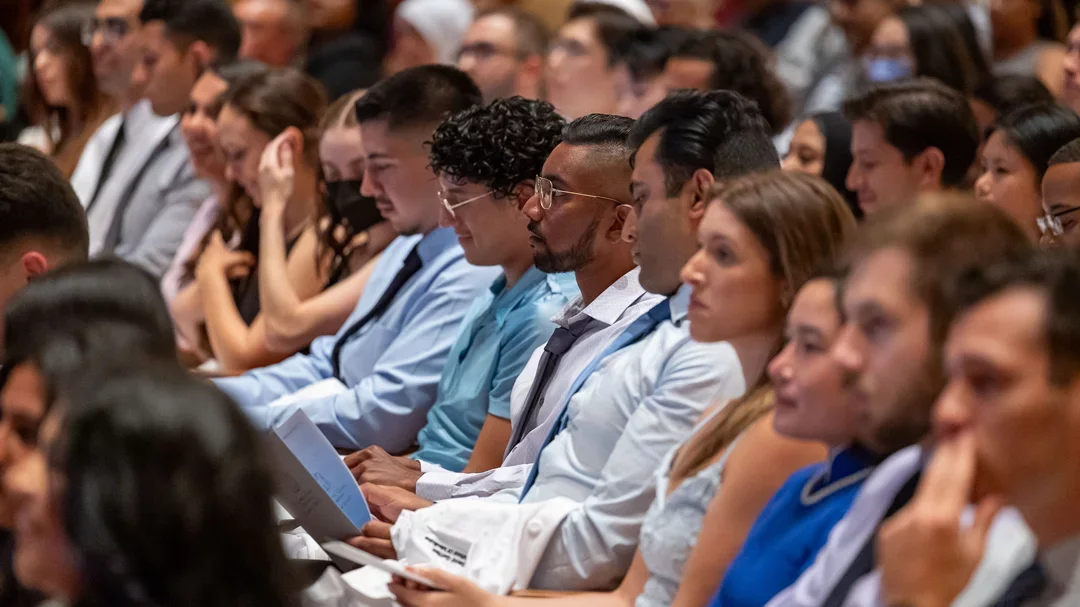 A group of medical students in an auditorium listening to a keynote.