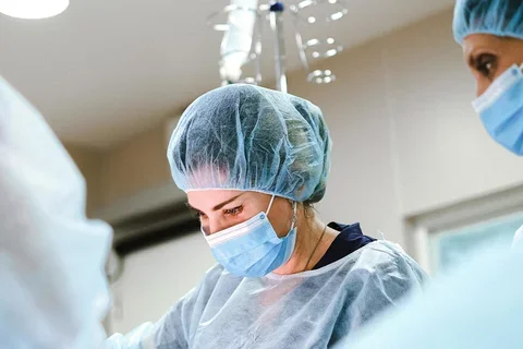Doctors in scrubs standing over a patient on an operating table