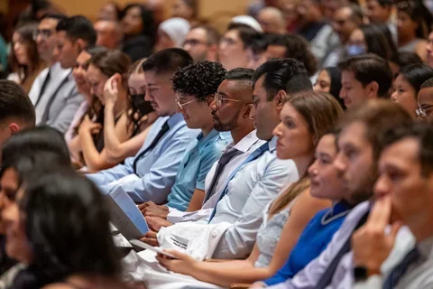 A group of medical students in an auditorium listening to a keynote.